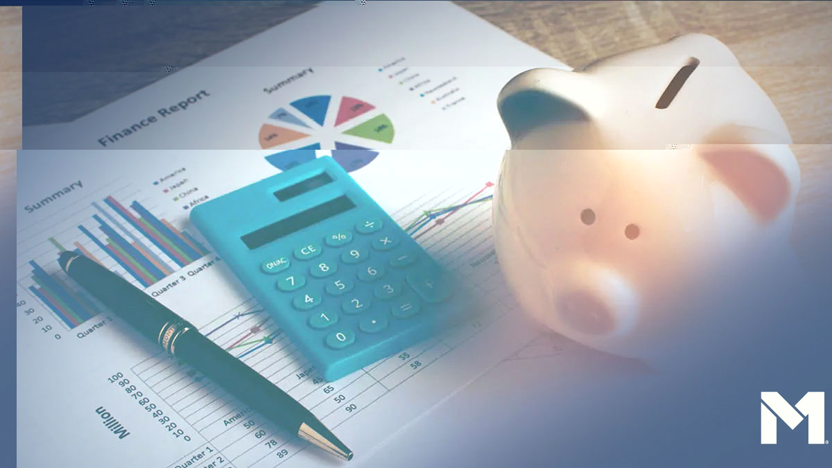 A desk with a piggy bank, a calculator, and a pen sittig on top of a financial report showing charts and graphs.