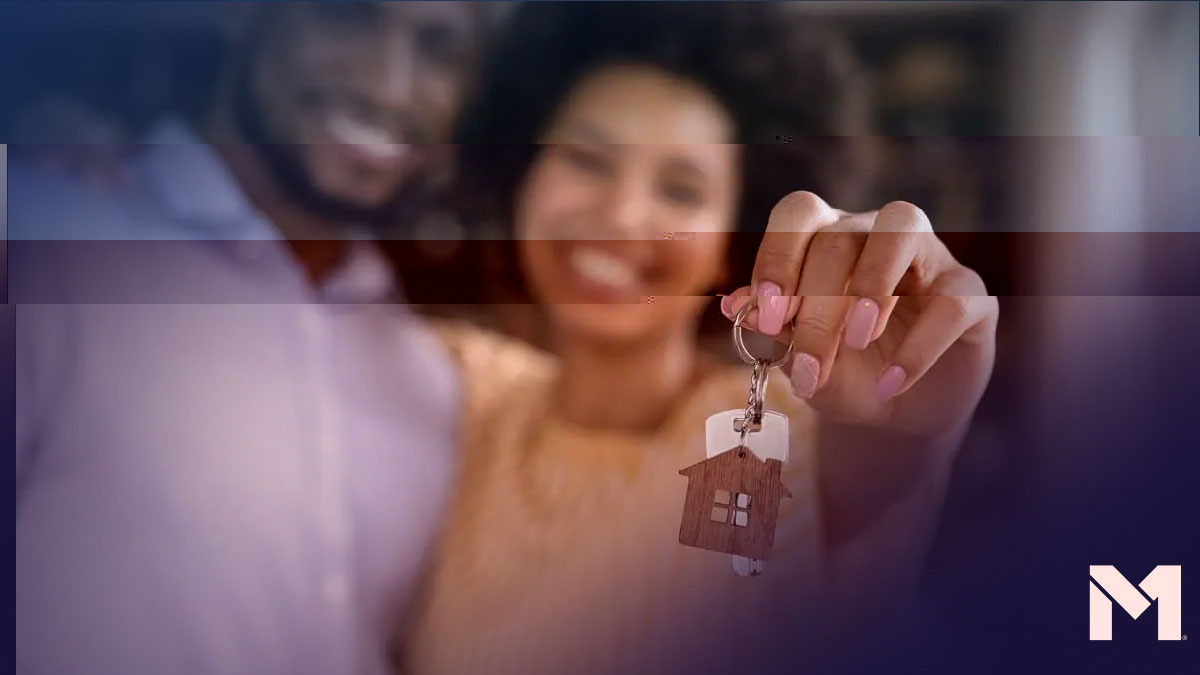 Two people holding up a set of keys with a house-shaped keychain attached to it, likely the keys to their new home.